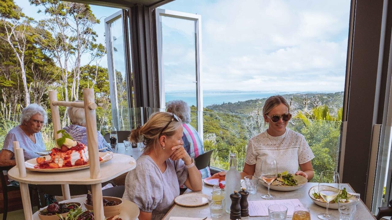 Outdoor lunch table set with gourmet food overlooking vineyards and the ocean on Waiheke Island