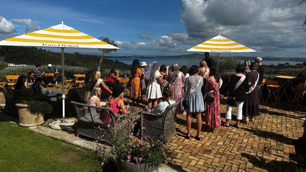 Wine and food served outdoors under the sun at a Waiheke Island vineyard with scenic views