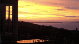 Couple dining outdoors under bright orange sunset skies on Waiheke Island