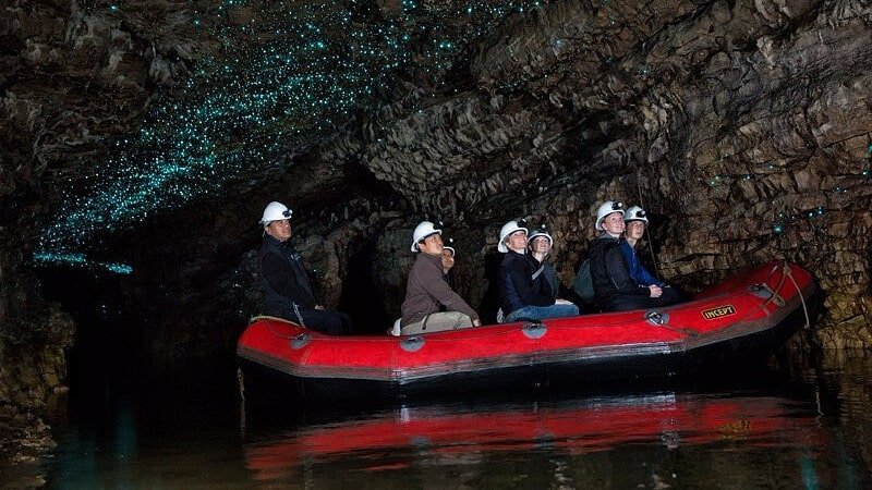 Small group on a raft entering the illuminated Waitomo Glow Worm Caves in New Zealand