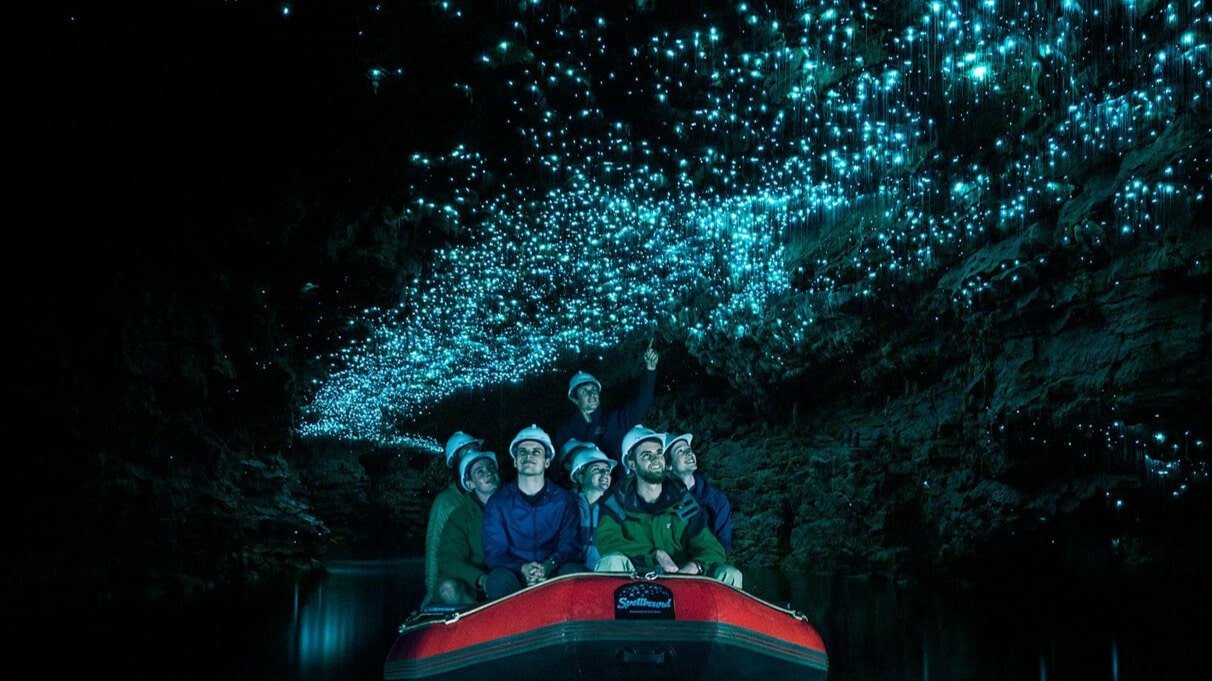 Visitors on a raft boat drifting quietly through the illuminated Waitomo Glow Worm Caves