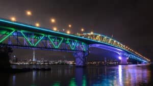 Night kayaking tour under the illuminated Auckland Harbour Bridge with city lights reflecting on the water