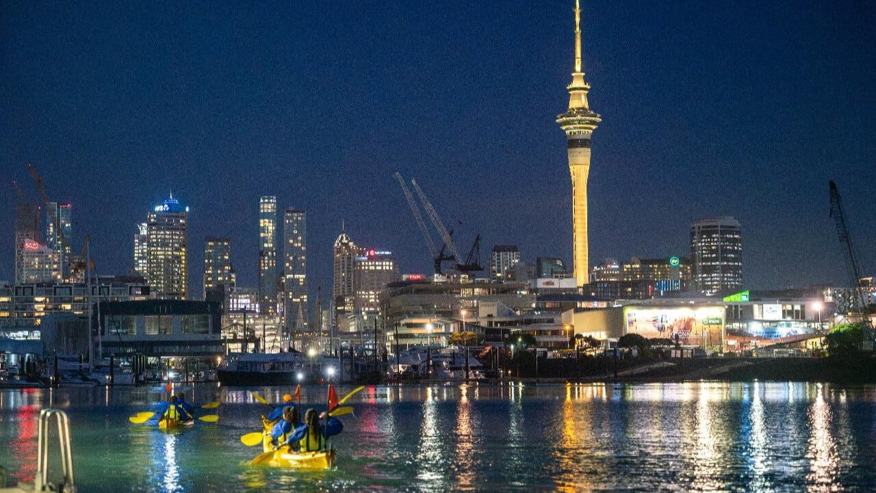 Night kayak tour with views of Auckland city lights and Sky Tower in the background