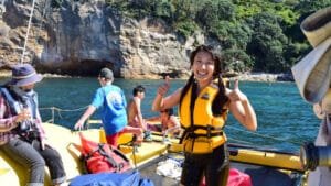Smiling woman giving two thumbs up on a catamaran cruise from Flaxmill Bay, with kids and bubbles onboard