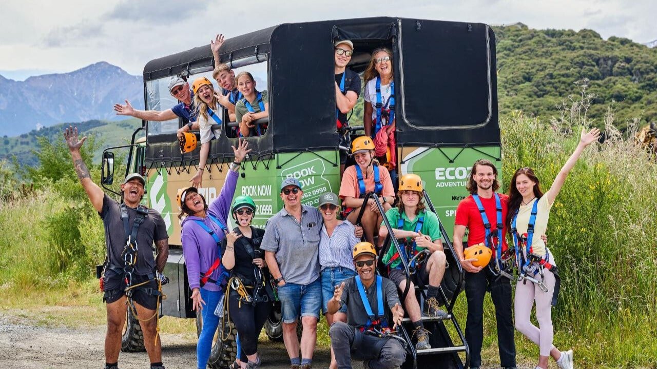 Group smiling in a rugged 4x4 Unimog truck before ziplining in Kaikōura