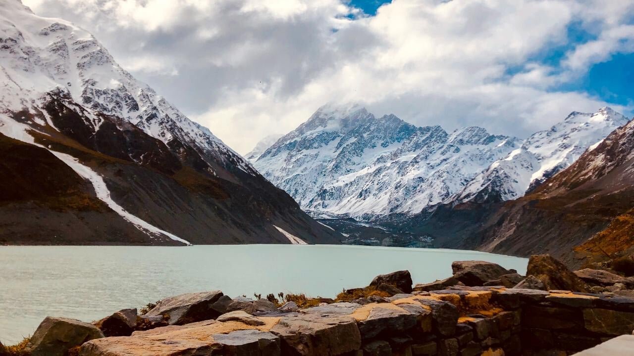 View over a pristine lake with snow-capped Mount Cook mountains in the background on a day tour from Christchurch via Tekapo