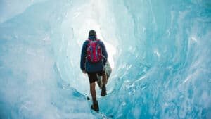 Person tramping through striking blue ice caves on a Mount Cook scenic tour from Queenstown