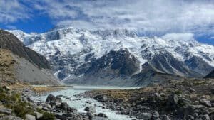 River flowing over rocks with snow-capped mountains in the background on Mount Cook scenic tramp tour from Queenstown