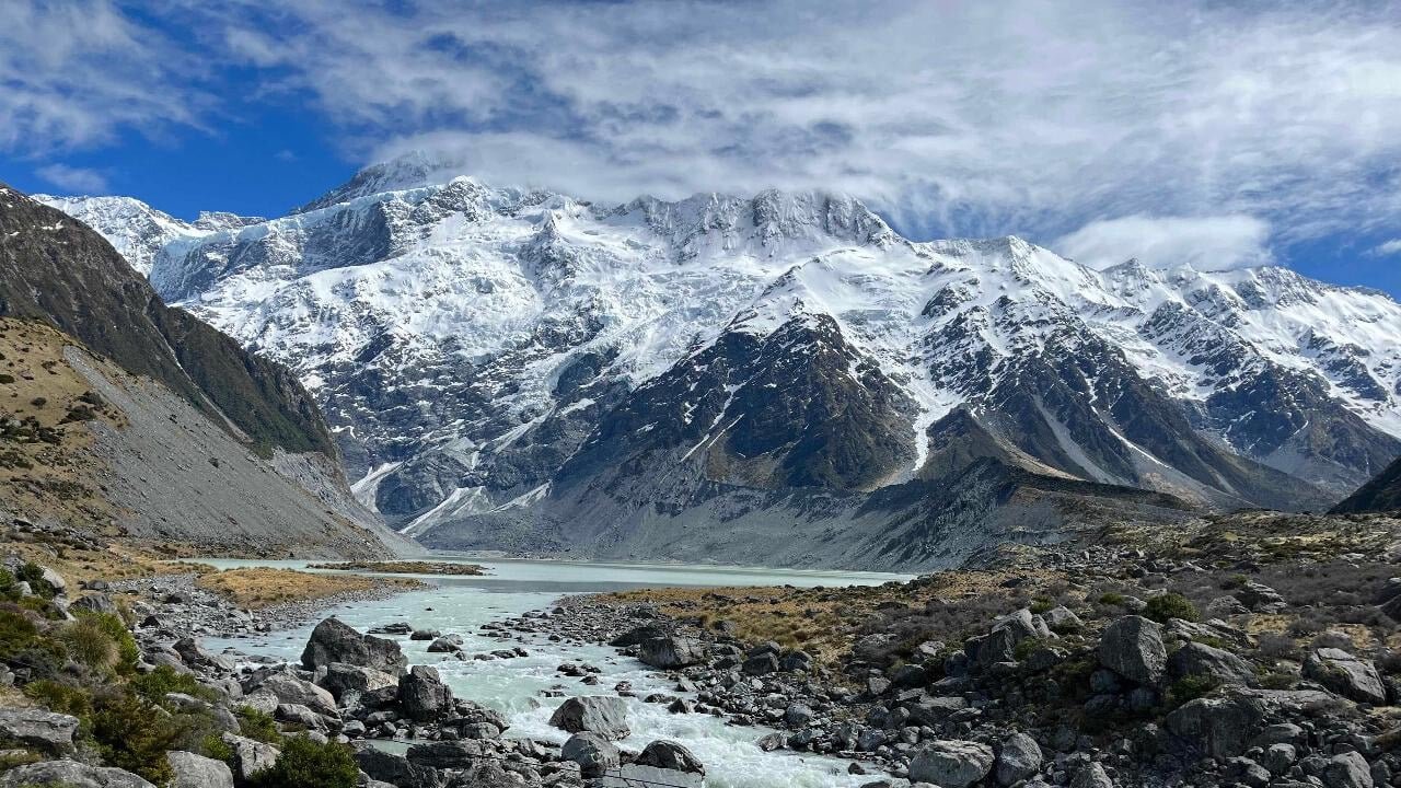 River flowing over rocks with snow-capped mountains in the background on Mount Cook scenic tramp tour from Queenstown