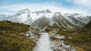 Rocky tramping paths leading toward snowy mountain peaks on Mount Cook scenic tour from Queenstown