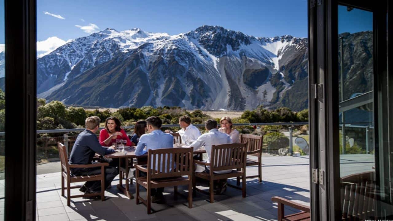 Small group enjoying an outdoor lunch with panoramic views of snow-capped Mount Cook and Tasman Glacier