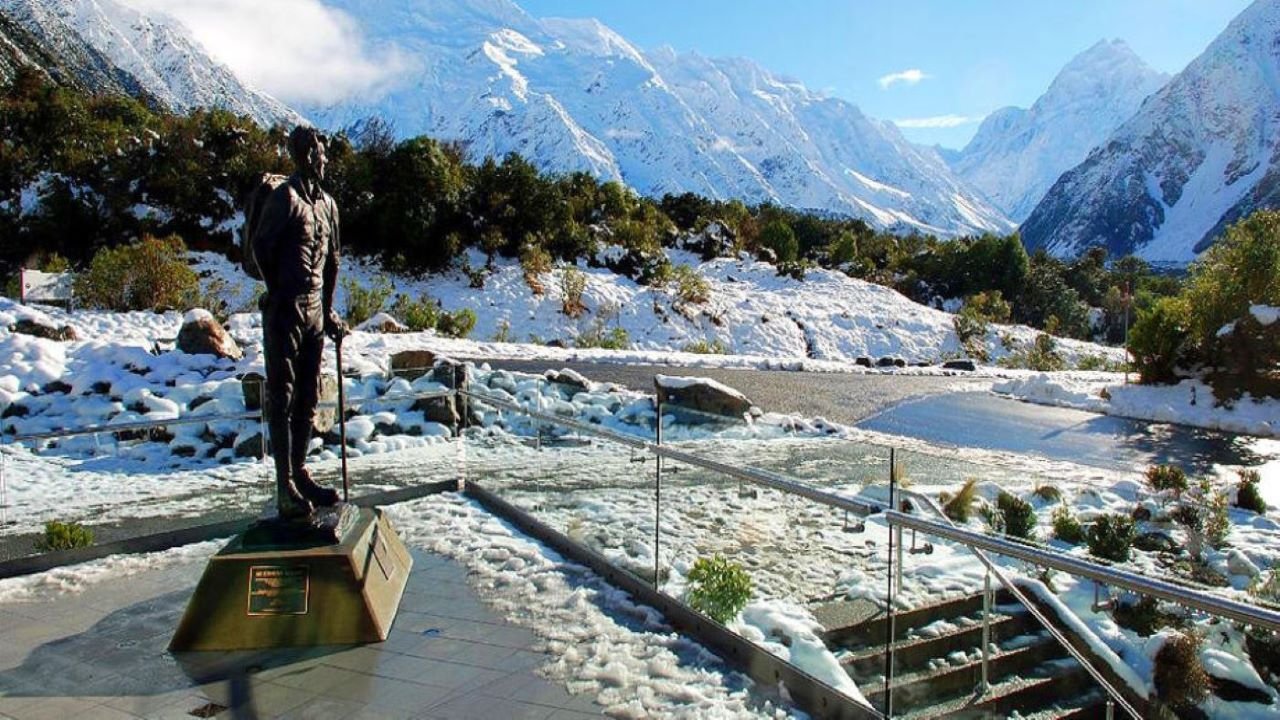 Bronze statue overlooking snow-capped mountains and icy Tasman Glacier on a Mount Cook tour from Queenstown
