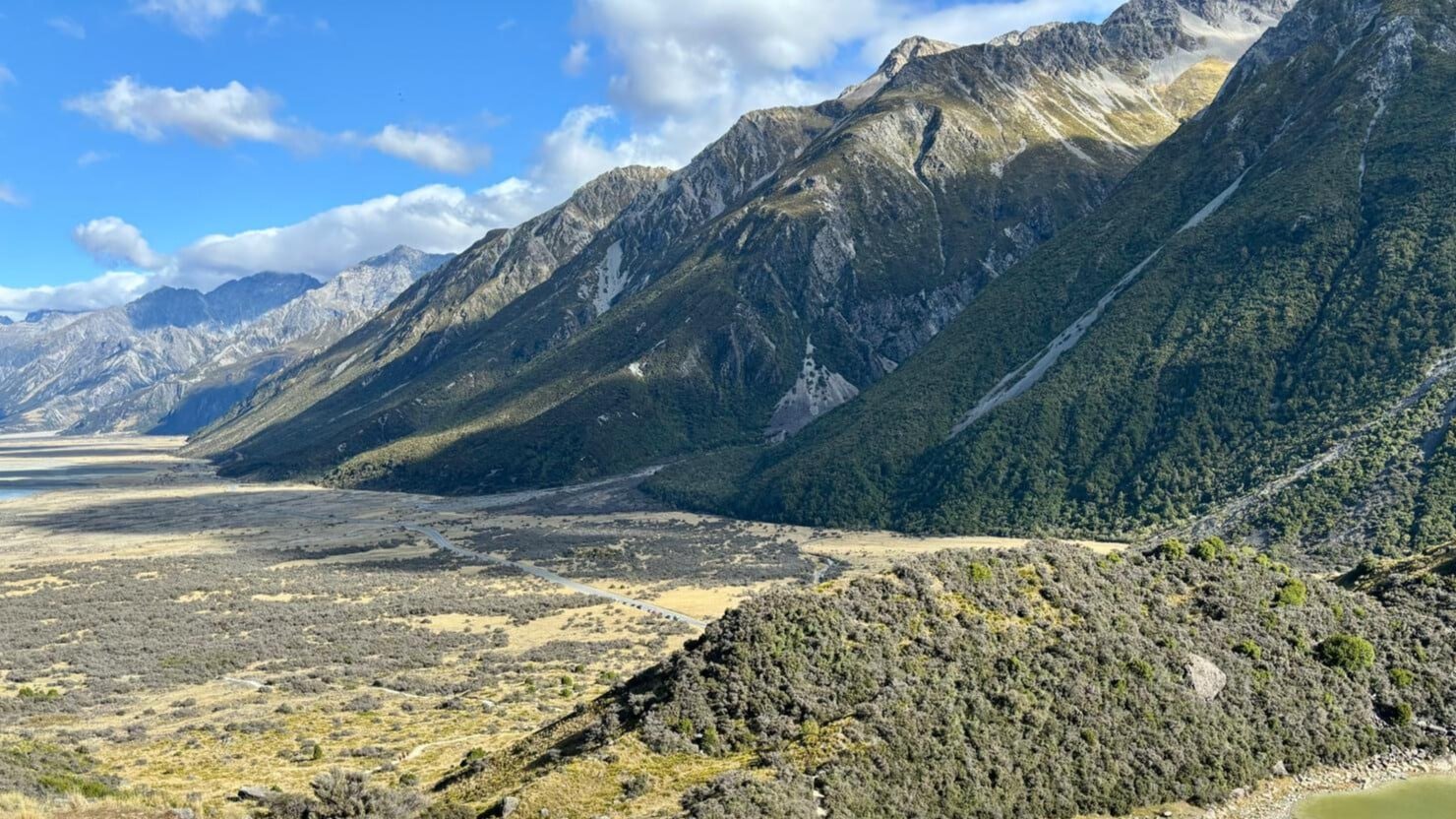 Lush green mountains and tramping path leading toward Tasman Glacier viewpoint on a Mount Cook tour from Queenstown