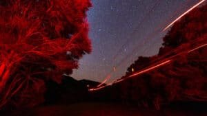 Night-time ziplining under red safety lights with a star-filled sky during the Kaikōura Star Flight experience