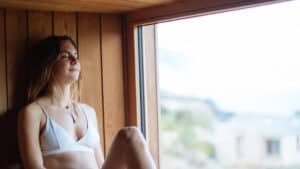Woman relaxing in a cedar sauna with alpine views at Aro Hā Wellness Retreat in New Zealand
